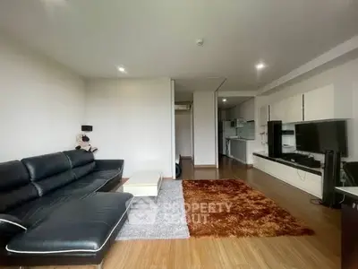 Spacious modern living room with sleek black sofa and open kitchen layout