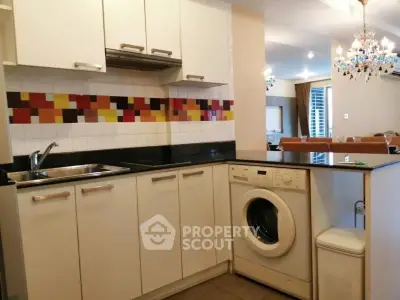 Modern kitchen with washing machine and colorful backsplash in open layout design.