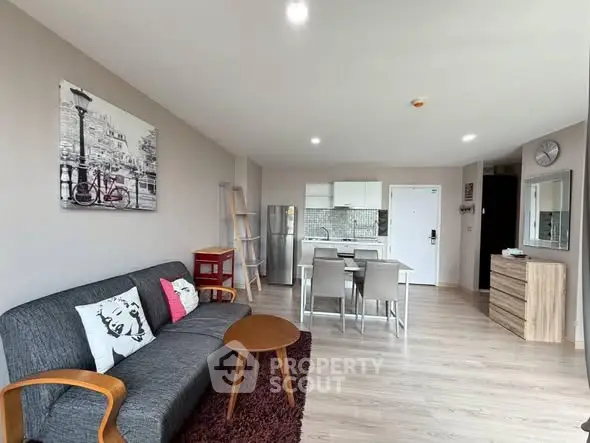 Modern living room with stylish decor and open kitchen layout, featuring sleek furniture and bright lighting.