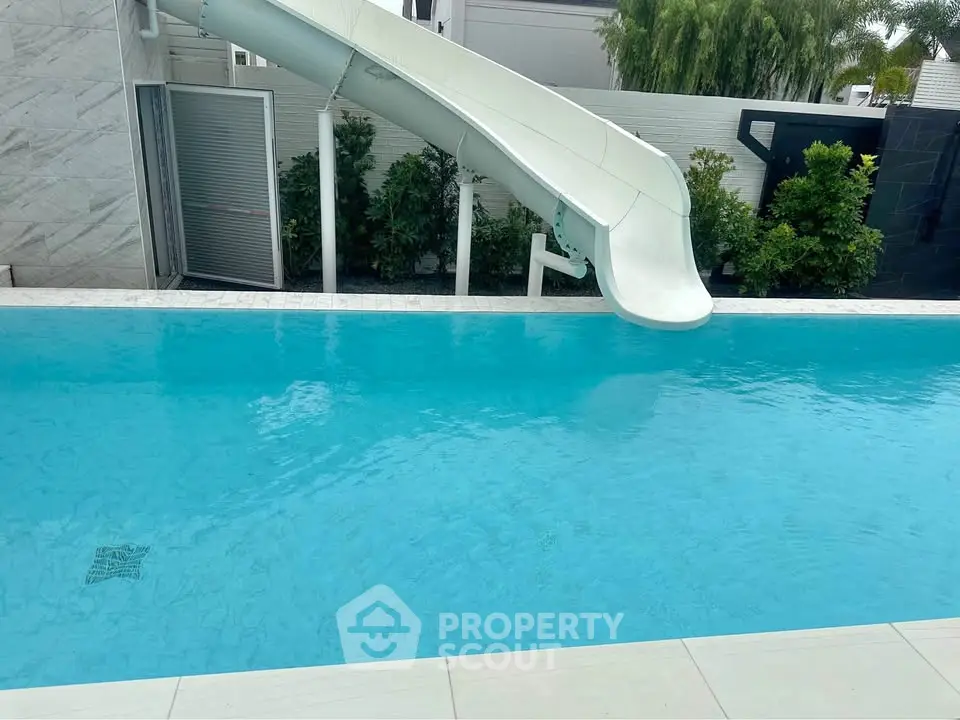 Luxurious outdoor pool with slide in modern residential property, perfect for family entertainment and relaxation.