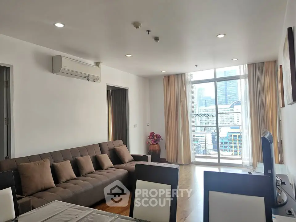 Spacious living room with city view and modern furnishings in high-rise apartment.