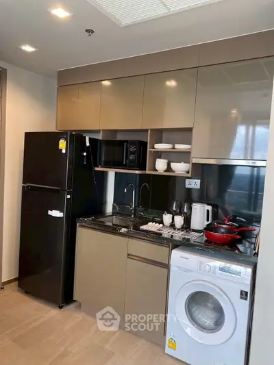 Modern kitchen with sleek cabinetry, washing machine, and appliances in a stylish apartment.