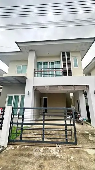 Modern two-story house with balcony and gated driveway in suburban neighborhood.