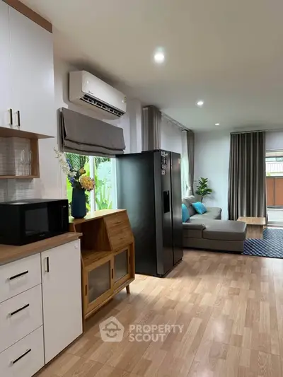 Modern living room with sleek kitchen, featuring stylish furniture and large fridge, perfect for contemporary living.