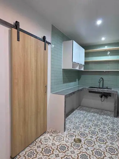 Modern kitchen with stylish tile flooring and sleek cabinetry, featuring a sliding barn door and open shelving.