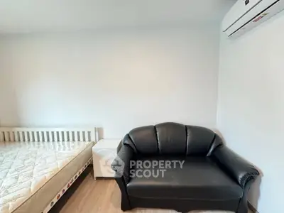 Cozy bedroom with black leather sofa and air conditioning, perfect for relaxation.