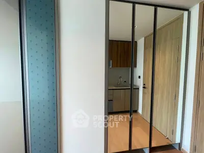 Modern kitchen with sleek cabinetry and mirrored closet doors in a stylish apartment.