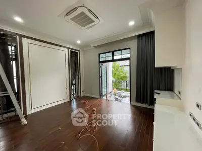 Spacious modern living room with wooden flooring and balcony access, perfect for stylish urban living.