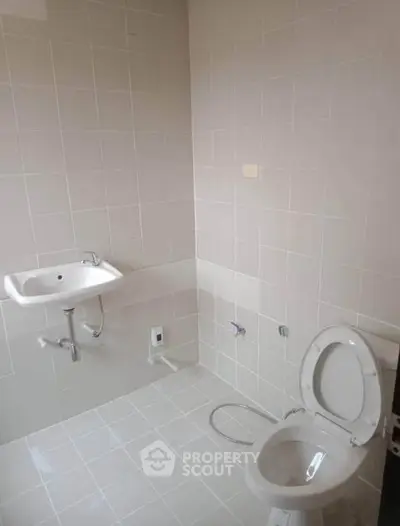 Minimalist bathroom with white tiles and basic fixtures, ideal for modern living.