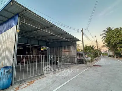 Spacious industrial-style garage with metal roofing and gated entrance, perfect for storage or workshop use.