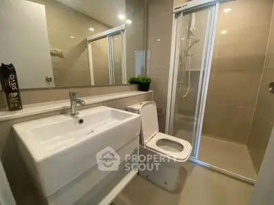 Modern bathroom with sleek fixtures and glass shower enclosure.