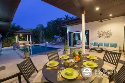 Luxurious tropical villa with private pool and outdoor dining area at dusk.