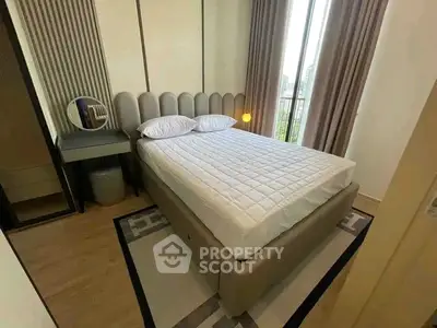 Modern bedroom with stylish decor and large window offering natural light.