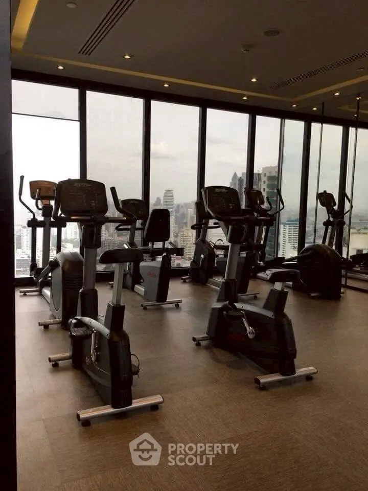 Modern gym with city view and exercise equipment in high-rise building.
