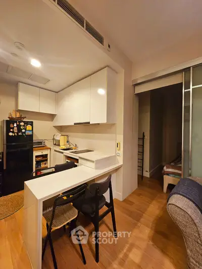 Modern kitchen with open layout and sleek white cabinets in cozy apartment.