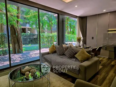 Luxurious living room with large windows overlooking lush greenery, featuring modern decor and cozy seating.