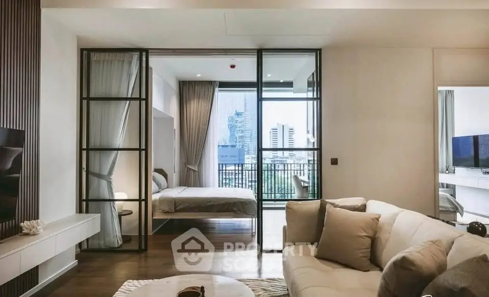 Modern open-plan living room with sliding glass doors leading to a bedroom and city view balcony.
