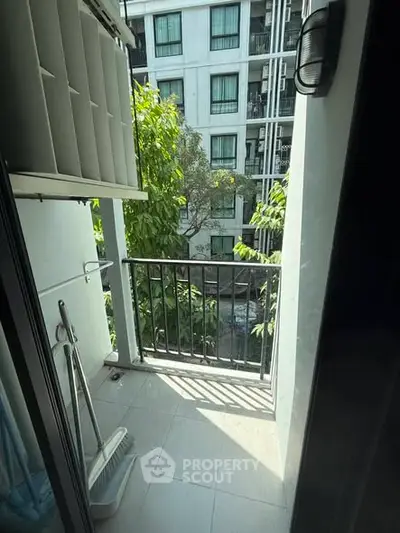 Charming small balcony with lush greenery view in modern apartment complex.