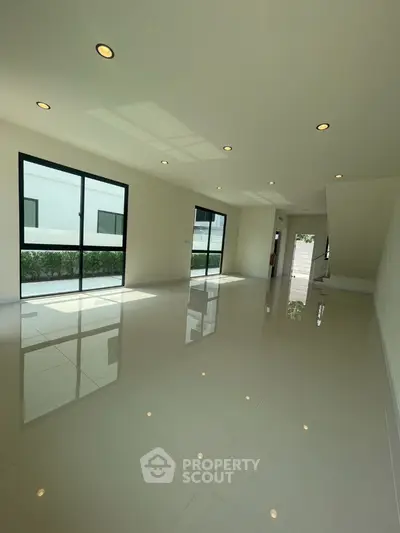 Spacious modern living room with large windows and glossy tiled floor