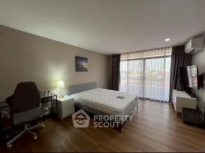 Spacious bedroom with modern decor and large window offering natural light.