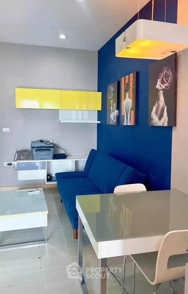 Modern living room with blue sofa, vibrant wall art, and sleek furniture in a stylish apartment.