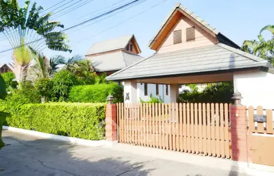 Charming suburban house with lush greenery and wooden gate, perfect for family living.