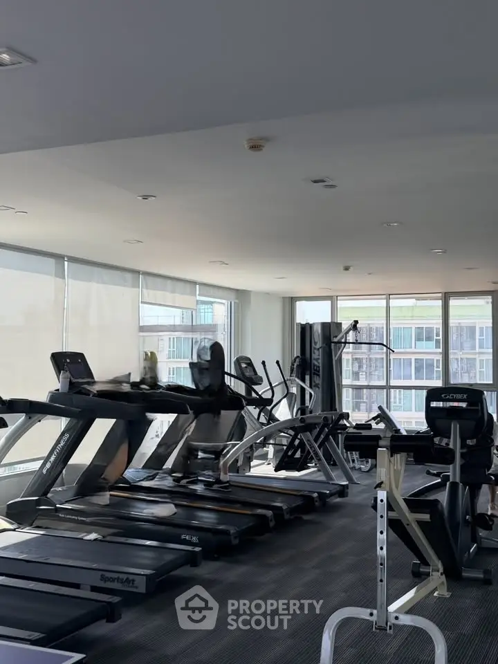 Modern gym with state-of-the-art equipment and panoramic city views, perfect for fitness enthusiasts.