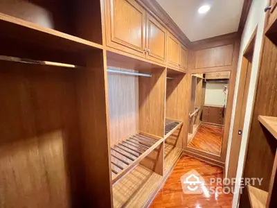 Spacious walk-in closet with wooden shelves and polished flooring