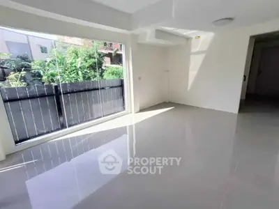 Spacious sunlit living room with large windows and glossy floors, perfect for modern living.