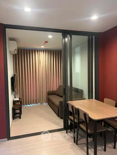 Modern living room with sliding glass doors, cozy sofa, and elegant dining table in stylish apartment.