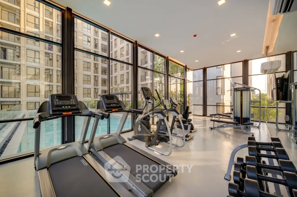 Modern gym with state-of-the-art equipment and pool view in luxury apartment complex.