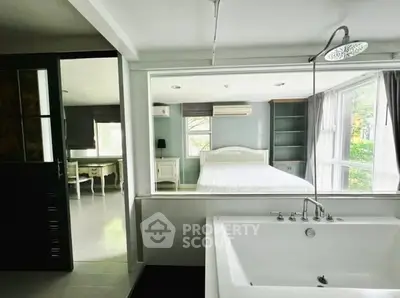 Spacious bedroom with ensuite bathroom featuring a modern bathtub and large windows for natural light.