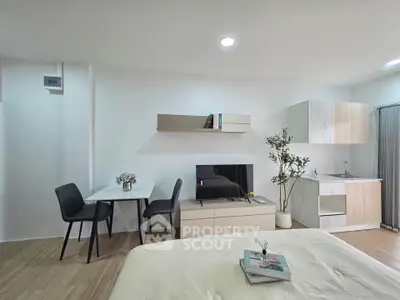 Modern studio apartment with sleek furniture and compact kitchen area, perfect for urban living.