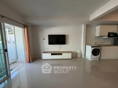 Modern living room with wall-mounted TV and washing machine, open layout design.