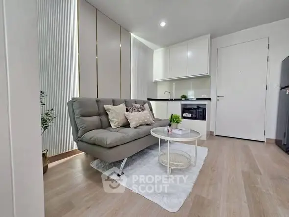 Modern living room with sleek kitchen, cozy sofa, and stylish decor in a contemporary apartment.