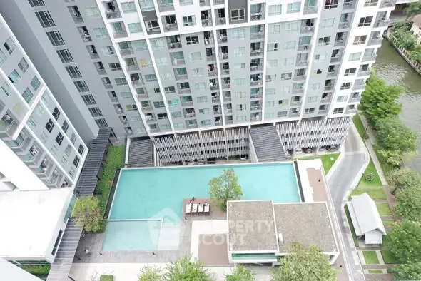 Stunning aerial view of modern high-rise building with luxurious pool and lush greenery.