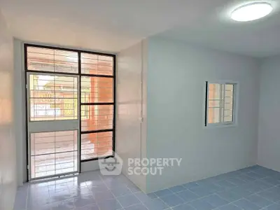 Bright room with large window and tiled floor, ideal for versatile living space.