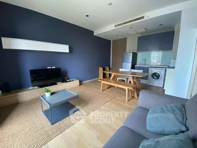 Modern living room with open kitchen, stylish furniture, and natural light.