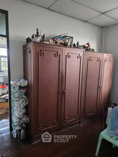 Spacious room with wooden wardrobe and natural light, ideal for storage and organization.