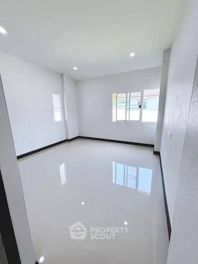 Spacious empty room with glossy tiled floor and bright natural light.