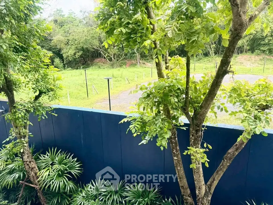 Lush garden view with vibrant greenery and modern blue fence, perfect for nature lovers.