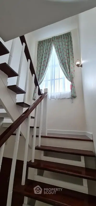 Charming staircase with wooden steps and floral curtains, perfect for cozy home ambiance.