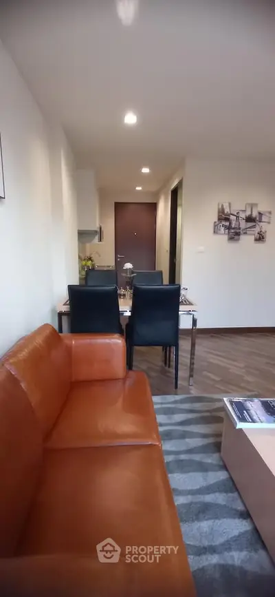 Modern living room with stylish leather sofa and dining area in open layout apartment.