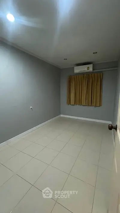 Spacious empty room with tiled flooring and air conditioning, perfect for customization.