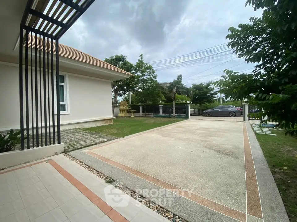 Spacious driveway and garden area of a modern home with lush greenery and ample parking space.