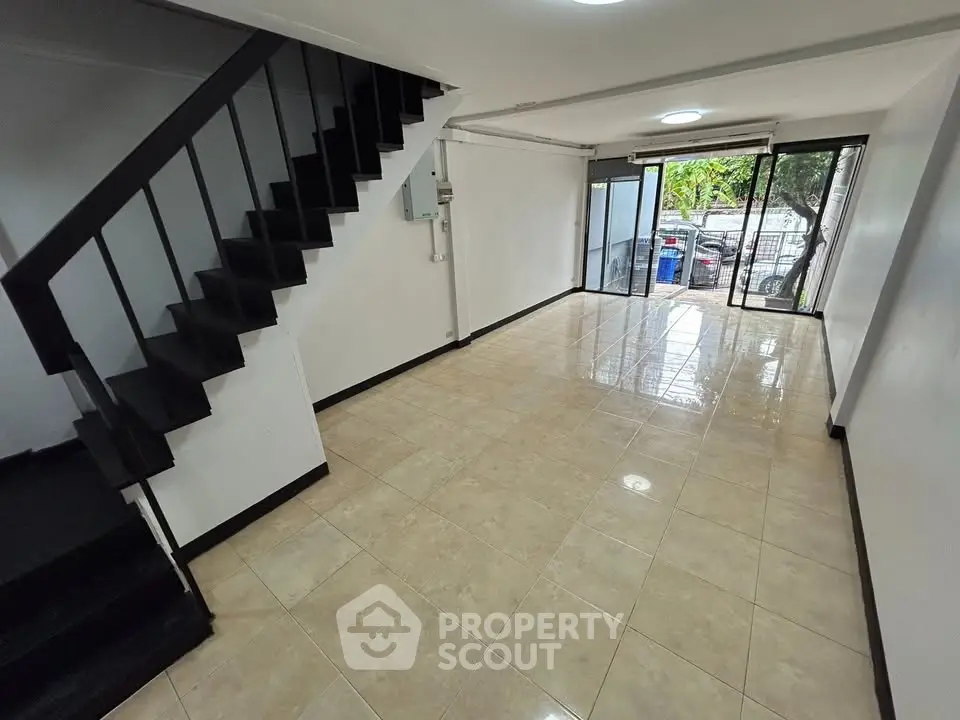 Spacious open-plan living area with large windows and modern staircase, perfect for natural light and contemporary living.