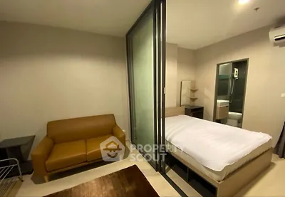 Modern studio apartment with cozy living area and glass partitioned bedroom.
