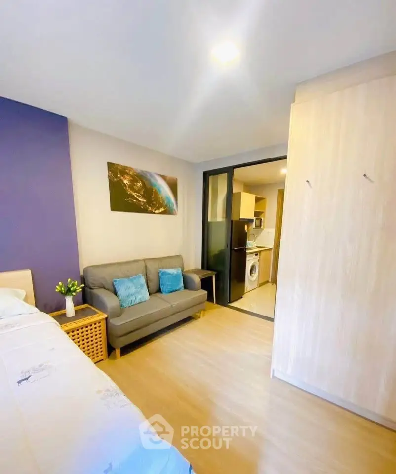 Modern studio apartment with cozy living area and compact kitchen featuring washing machine.