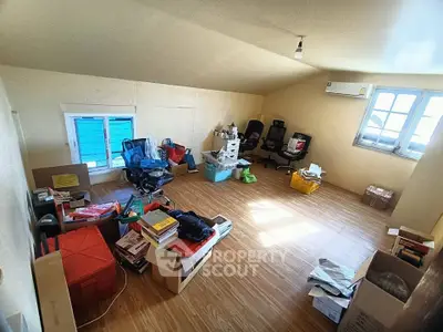 Spacious attic room with wooden flooring and ample natural light, ideal for storage or creative workspace.