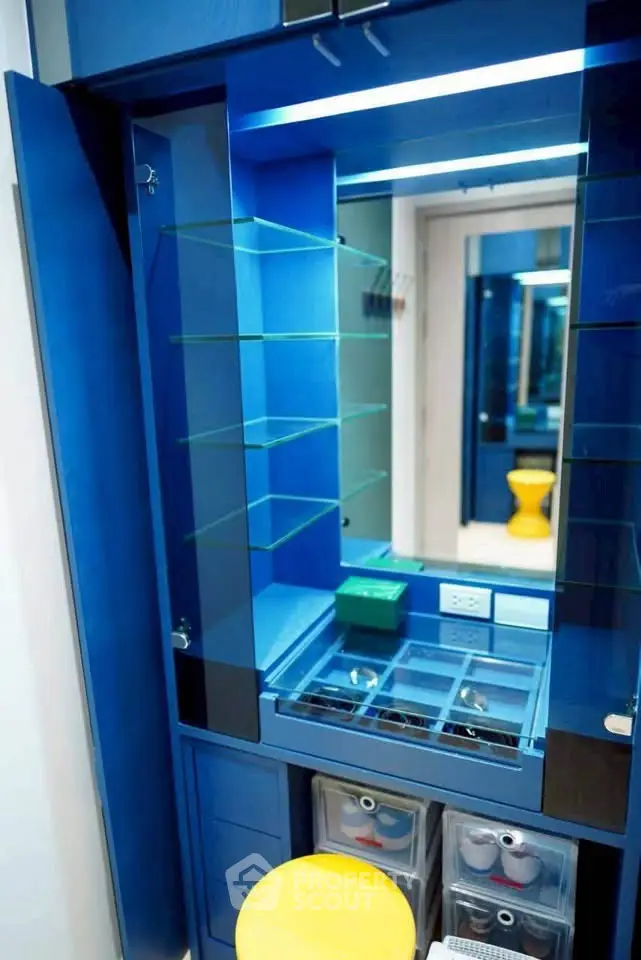 Modern blue storage unit with glass shelves and mirror in stylish interior design.